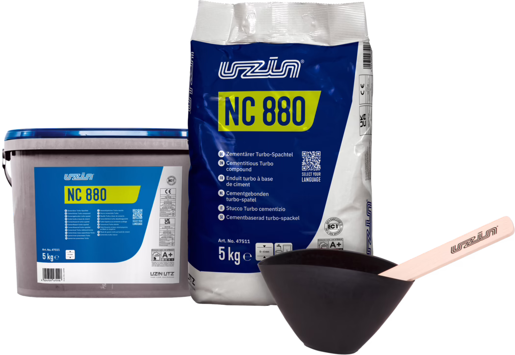 UZIN_Dummy_NC 880-5kg set_2024-08 Två förpackningar av UZIN NC 880 cementbaserat turbo-spackel: en blå-vit 5 kg säck och en matchande 5 kg plastburk, fotograferade med en svart blandningsskål och en träspackel; produktetiketter och QR-kod synliga.