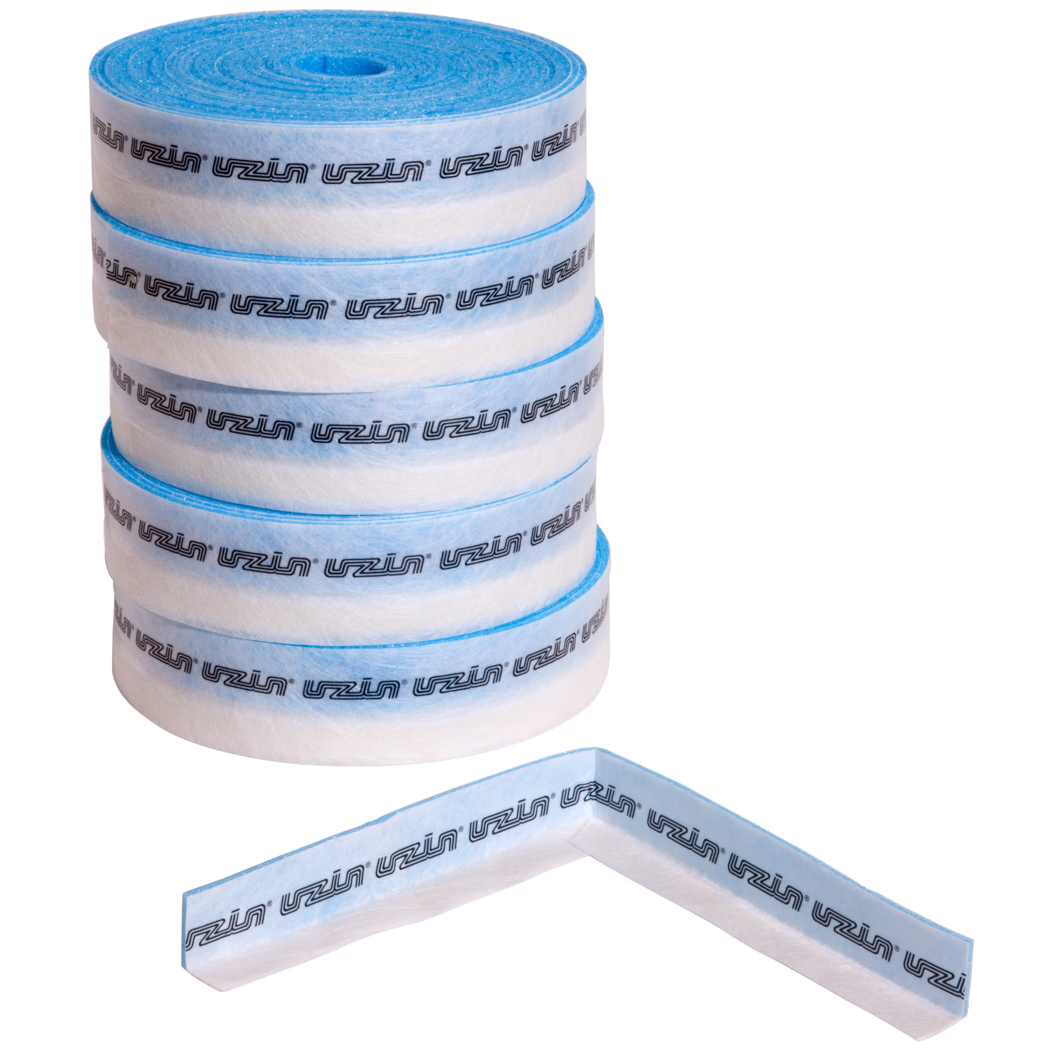 UZIN_Dummy_ESB 50_5_2014-02 Fem staplade rullar av vit och ljusblå icke-vävt tätningsband, med en L-formad rem framför. Bandet visar ett upprepat svart 'uzin'-logotyp längs hela längden. Materialet ser fiberrikt ut med en klibbig kant och är avsett för tätning av hörn och vattentätning vid kakelarbete och bygg. Foto mot vit bakgrund.